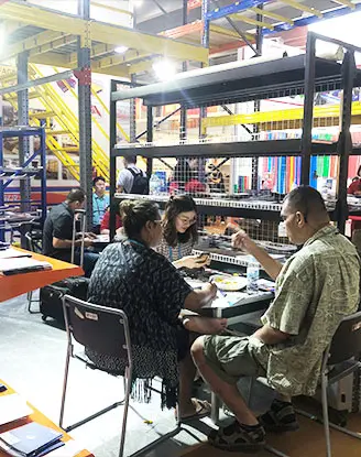 Warehouse operators reviewing industrial shelving components at booth